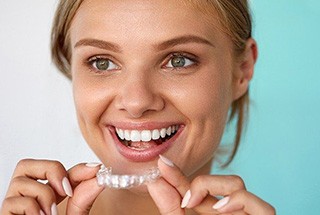 Woman smiling while holding clear aligner