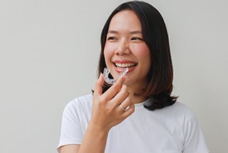 Woman smiling while holding clear aligner