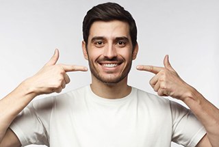 Smiling man pointing at his mouth