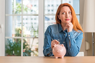 woman and piggy bank for cost of teeth whitening McKinney