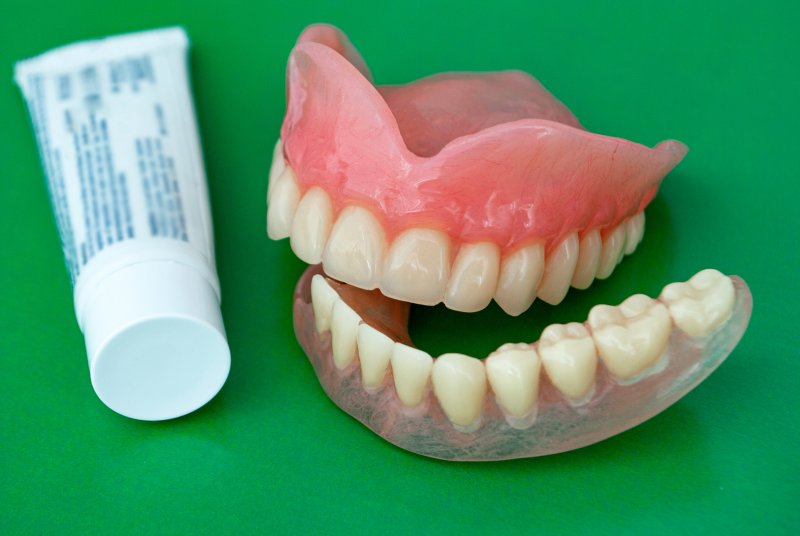 A tube of denture adhesive and dentures