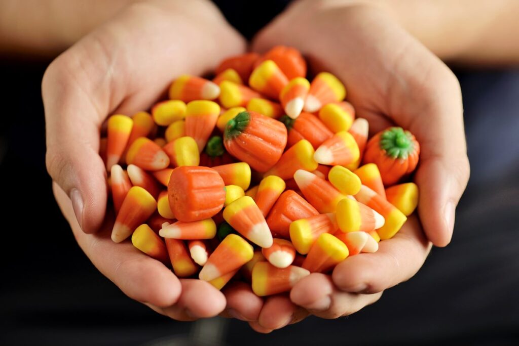 A person holding two handfuls of candy corn.